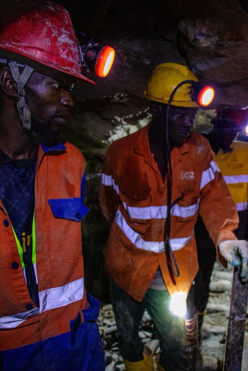 Two miners working underground by headlamp.