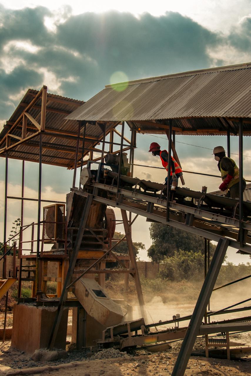 Workers tending an ore conveyor at a gold processing plant.