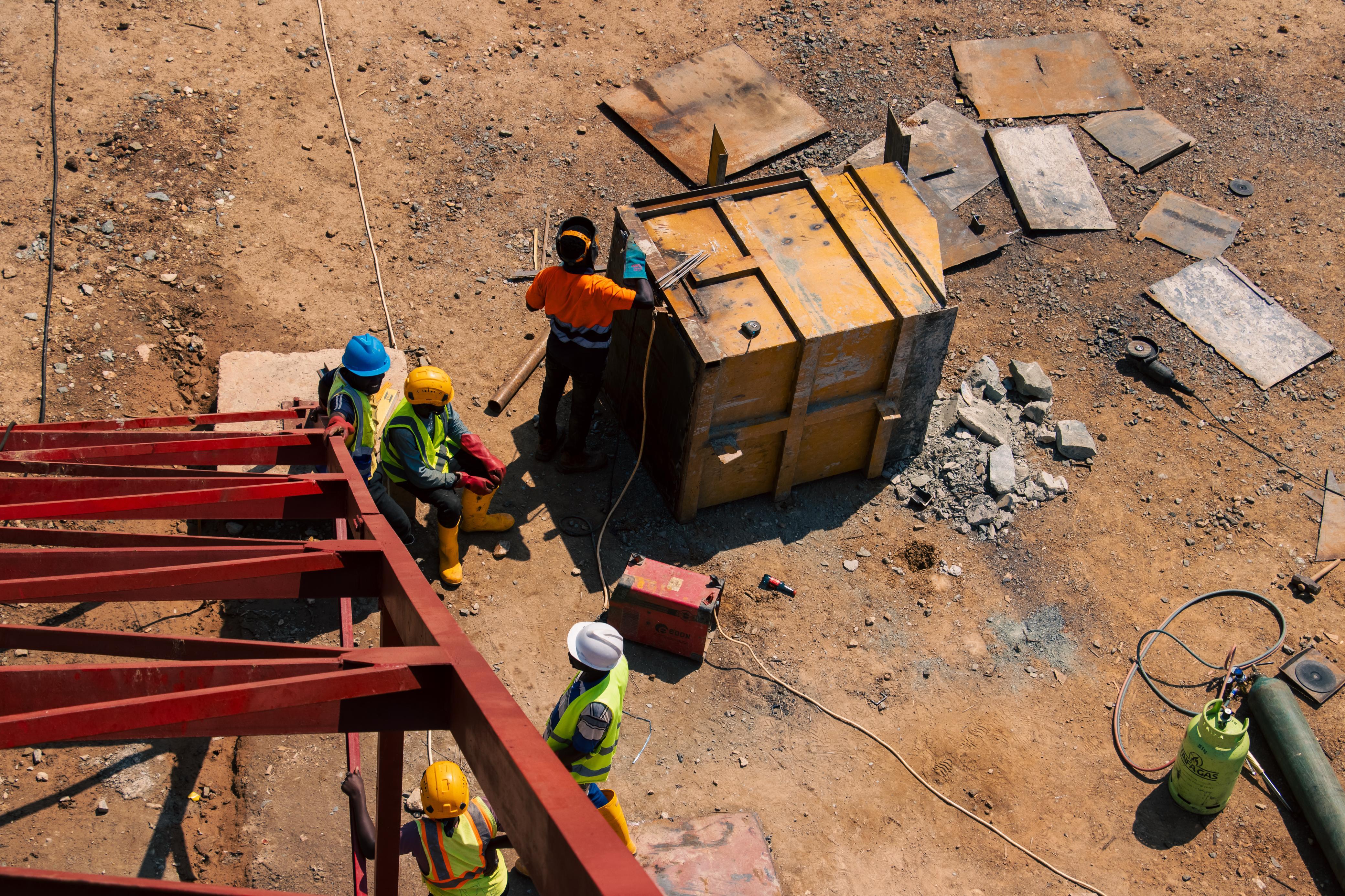 Workers assembling steel structures on a mine site, seen from above.