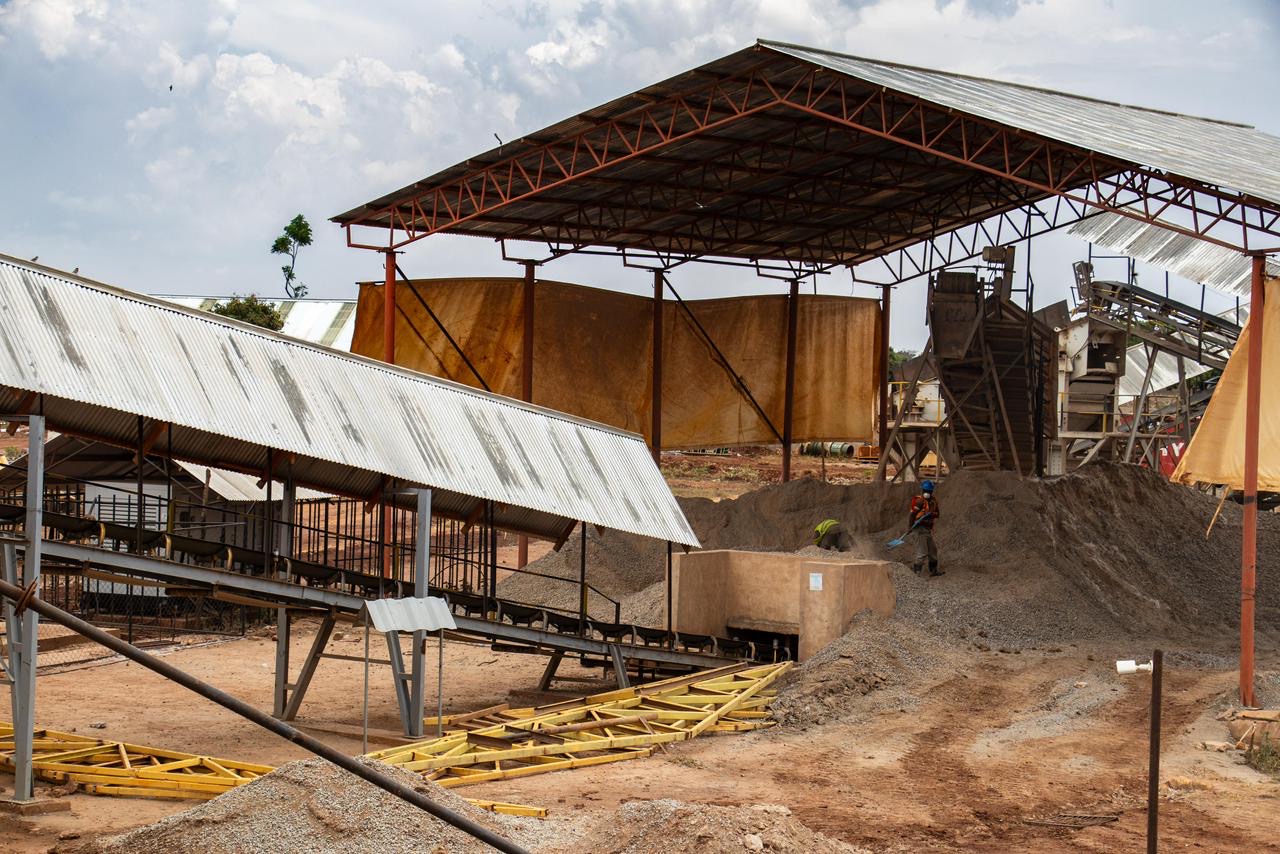 A gold processing plant with open sheds, conveyors and ore stockpiles.