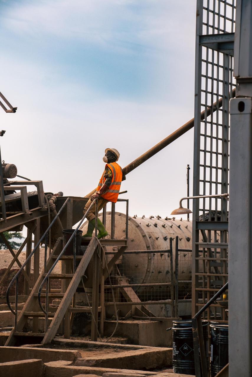 A worker beside a ball mill at a gold processing plant.