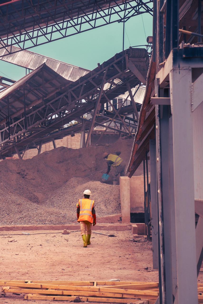 A worker walking toward crushed-ore stockpiles at a processing plant.